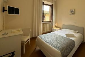 a bedroom with a bed and a desk and a window at Monastero SS. Annunziata in Todi