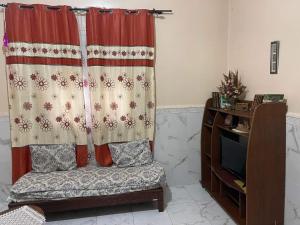 a living room with a curtain and a couch and a tv at Two bedroom with garden in Constantine