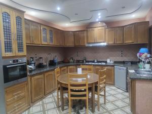 a kitchen with wooden cabinets and a table and chairs at Villa chadine in Safi