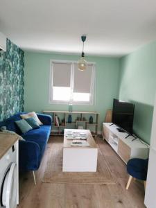 a living room with a blue couch and a tv at Charmante maison rénovée en plein centre in Saint-Nazaire