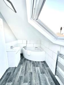 a white bathroom with a tub and a window at Beautiful quiet Victorian Bungalow heart of London in London