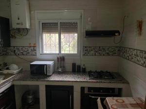 La cocina está equipada con fogones y microondas. en Two bedroom with garden en Constantina