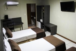 Una habitación de hotel con tres camas y un televisor. en Hotel Extasy (Adult Only), en São Vicente