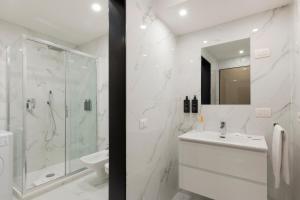 a white bathroom with a shower and a sink at Milan Royal Suites - Centro Duomo in Milan