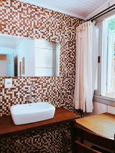 La salle de bains est pourvue d'un lavabo et d'un miroir. dans l'établissement Pousada Quinta dos Medeiros, à Canela