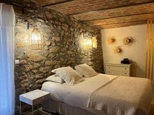 ein Schlafzimmer mit einem Bett und einer Steinmauer in der Unterkunft Domaine de la Bastidonne in Céreste