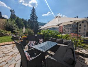 a patio with a table and chairs and an umbrella at Urlaubsmagie - Wohlfühlwohnung mit Balkon, Pool, Sauna & Terrasse - HW2b in Sebnitz