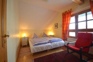 a bedroom with a bed and a red chair at Appartement "Romantika" in Klink
