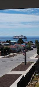 an empty street with a cruise ship in the ocean at Departamento Nuevo in Punta Arenas