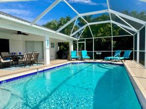 a swimming pool with blue chairs and a house at VILLA PALM ISLAND in Cape Coral