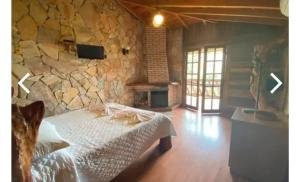 a bedroom with a stone wall with a bed in it at Pousada Peterle in Domingos Martins