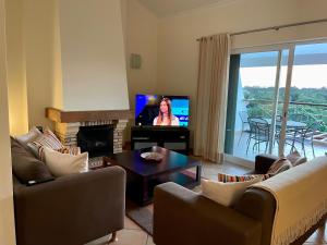 a living room with couches and a tv and a table at Boa Vida in Quarteira