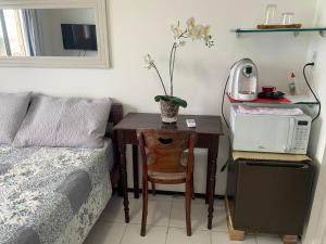 1 dormitorio con escritorio, cama y mesa con microondas en Adelaide Suite, en Fortaleza
