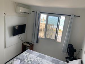 1 dormitorio con 1 cama, TV y ventana en Adelaide Suite, en Fortaleza