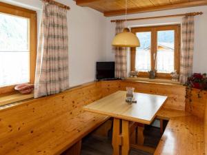 a dining room with a wooden table and two windows at Alpinechalet Zigjam in Gaschurn
