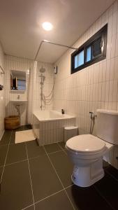 a bathroom with a toilet and a bath tub at Skugga Farm Cabin in Mae On