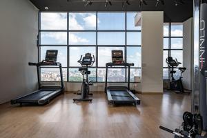 a gym with several tread machines in front of a large window at Elite One Bedroom Apartment,Swimming pool, gym, workspace ,Wonderiss Homes Westland Living in Nairobi