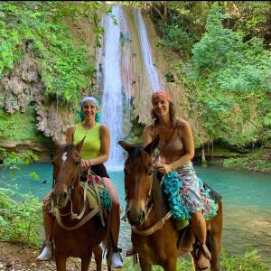 two women riding horses in front of a waterfall at Rancho Romana Retreat N-05 in El Limón