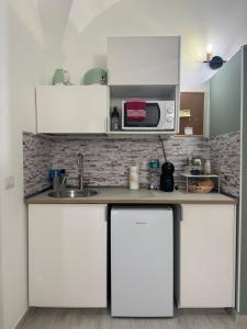 a kitchen with white cabinets and a microwave at Corte Capuana in Catania