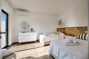 a white room with two beds and a mirror at PEAR TREE VILLA in Vale do Lobo