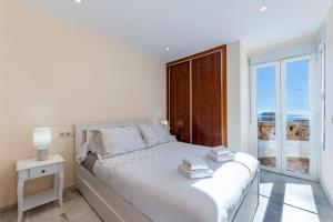a white bedroom with a bed and a large window at Chalet in Torrequebrada residencial golf urbanization in Torrequebrada