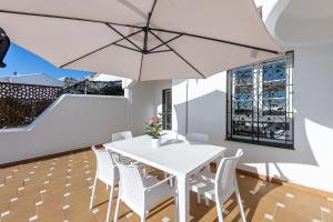 une salle à manger avec une table blanche, des chaises et un parasol dans l'établissement Chalet in Torrequebrada residencial golf urbanization, à Torrequebrada