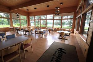 a dining room with tables and chairs and windows at Hotelli Heimari in Heimari