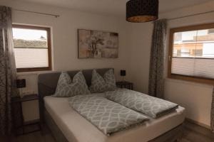 ein Schlafzimmer mit einem Bett und zwei Fenstern in der Unterkunft Apart Daniel in Ried im Oberinntal
