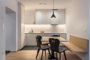 a kitchen with a wooden table and two chairs at Mountain Meadows Apt 4 in Valdaora