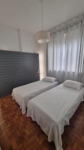 2 bedden in een kamer met witte lakens bij Apê in Copacabana in Rio de Janeiro