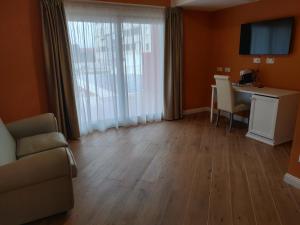 RMaison Luxury Suites Olbia في أولبيا: غرفة مع غرفة معيشة مع طاولة ومكتب