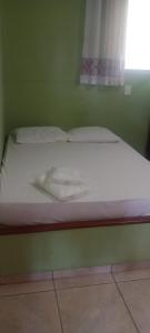 een wit bed in een groene kamer met een raam bij Agencia e Pousada - Capitolio - MG Melhor Custo Beneficio - Piscina - Campao de Futebol in Capitólio