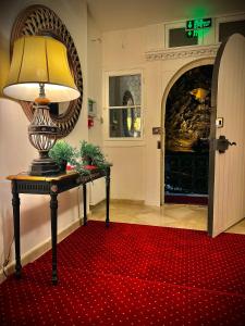 lampa na stole z czerwonym dywanem w obiekcie Vila Șipot - Casa Arhitecților w mieście Sinaia
