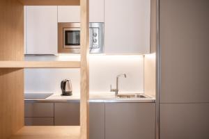 a kitchen with white cabinets and a sink and a microwave at Chalet Falorie in Cortina dʼAmpezzo