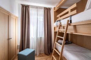 a bedroom with bunk beds with a ladder and a window at Chalet Falorie in Cortina dʼAmpezzo