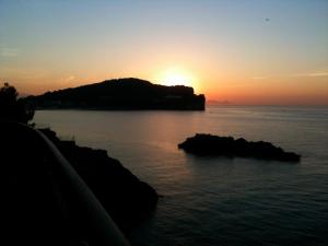 einen Sonnenuntergang über einem Wasserkörper mit einer Insel in der Unterkunft A casa di Andrea e Lucia in Gaeta