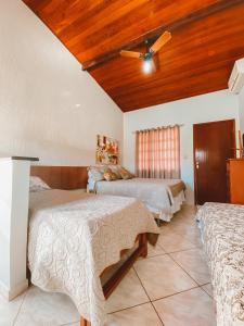a bedroom with three beds and a ceiling fan at Pousada Caminho do Mar in Cabo Frio