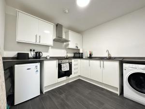 a kitchen with white cabinets and a washer and dryer at Cosy Studio Escape in Ilkeston with Netflix in Ilkeston