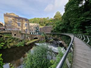 a bridge over a river next to a building at Over Torrs Cottage in New Mills