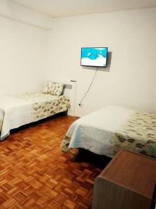 a bedroom with two beds and a flat screen tv on the wall at Florida Garden 624 in Buenos Aires
