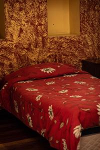 a bed with a red blanket with flowers on it at Hostal Imperial Carlos V in Potosí