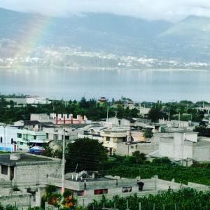 a city with a rainbow in front of a body of water at Green House Araque Inn in Otavalo