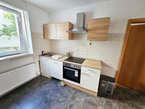 cocina con armarios blancos, fregadero y ventana en Ferienwohnung in zentraler Lage, en Frechen