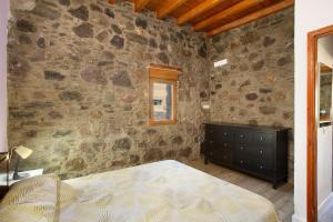 a bedroom with a stone wall with a bed and a dresser at Villa Paraiso Aldeano 1+2 in La Aldea de San Nicolas +22 photos