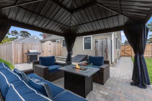 an outdoor patio with blue chairs and a fire pit at 3-min Walk To Beach! Private Luxury Backyard! in Dennis