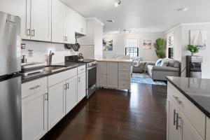 a kitchen with white cabinets and a living room at 3-min Walk To Beach! Private Luxury Backyard! in Dennis