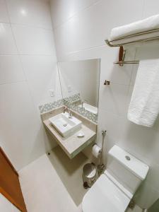 a white bathroom with a sink and a toilet at Pousada Caminho do Mar in Cabo Frio