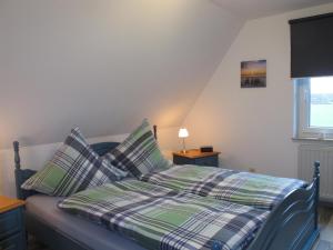 a bedroom with a bed with plaid sheets and a window at Ferienwohnung ERNA HORS110 in Wangerland