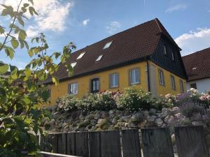 een geel huis met een zwart dak en een hek bij gemütliches Apartment mit Galerie im Ferienhof in Litzendorf