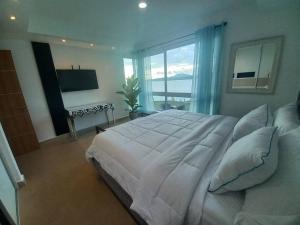1 dormitorio con 1 cama blanca grande y TV en Apartment in the Causeway Amador en Panamá
